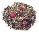 Cup of Raspberry Hibiscus tea by Sage & Stone Apothecary with fresh raspberries and hibiscus flowers on a wooden table.