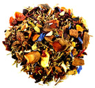 A cup of Sage & Stone Apothecary Spiced Pear tea with tea leaves and spices on a rustic wooden table.