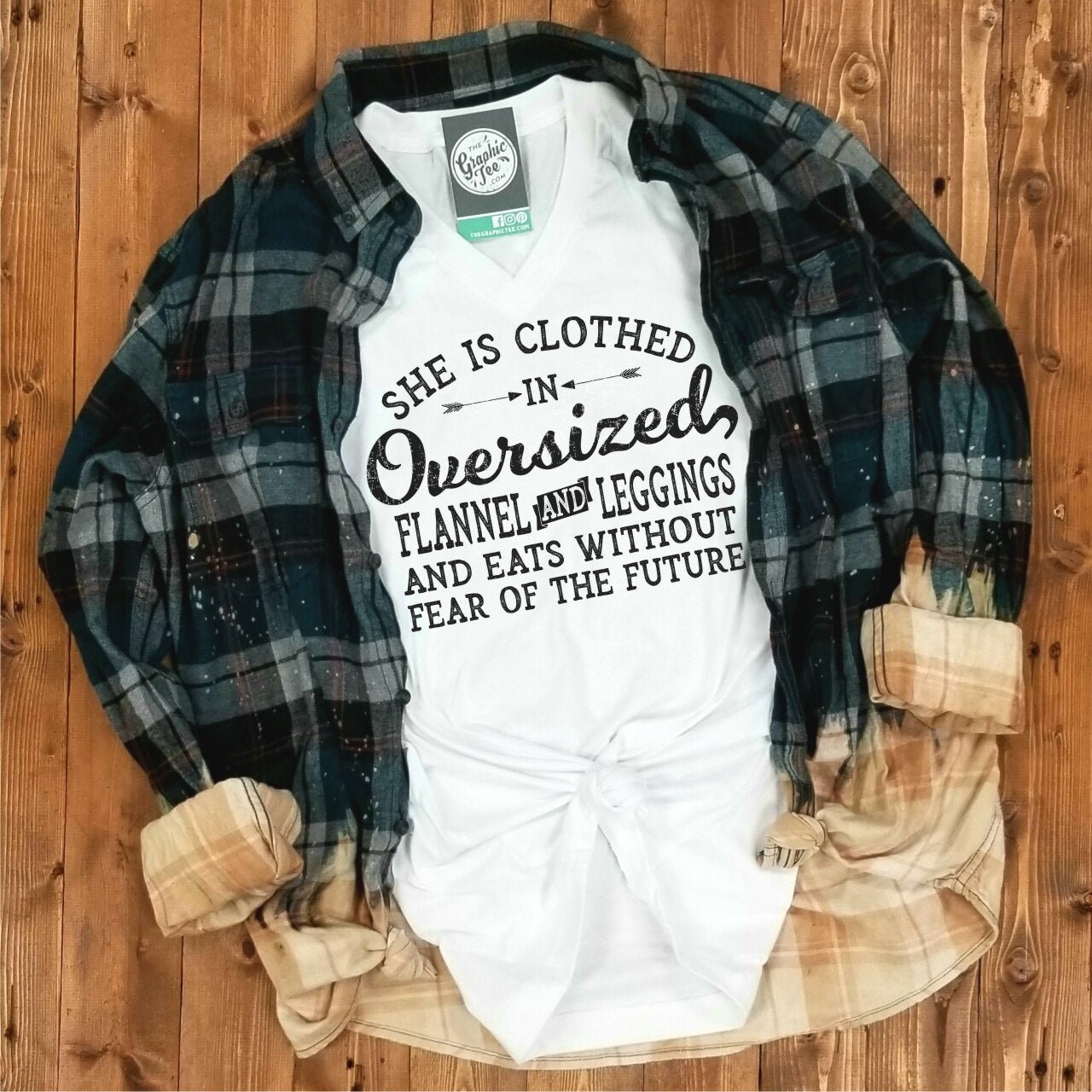 Woman wearing oversized flannel, leggings, and a V-neck graphic tee from The Graphic Tee brand. Casual, cozy outfit.