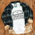 Woman wearing oversized flannel, leggings, and a V-neck graphic tee from The Graphic Tee brand. Casual, cozy outfit.