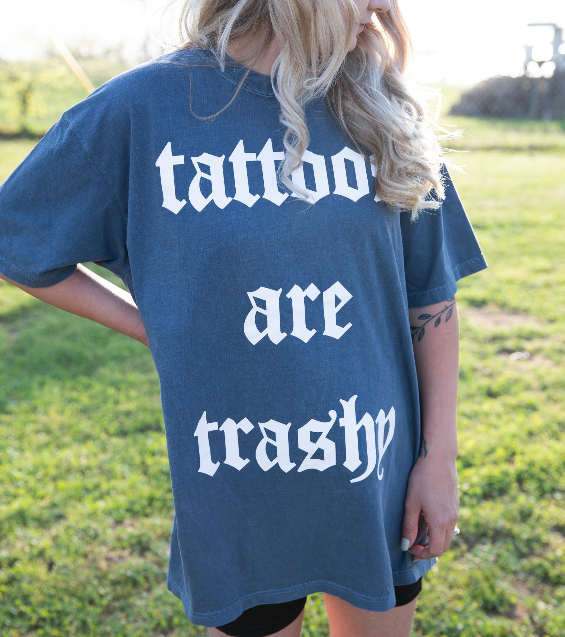 Black graphic T-shirt featuring bold "Tattoos are Trashy" design from Shop Karma Tees, displayed on a mannequin.
