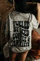 Black graphic tee featuring "Fueled by Iced Coffee and Anxiety" slogan from Shop Karma Tees, casual wear with bold design.