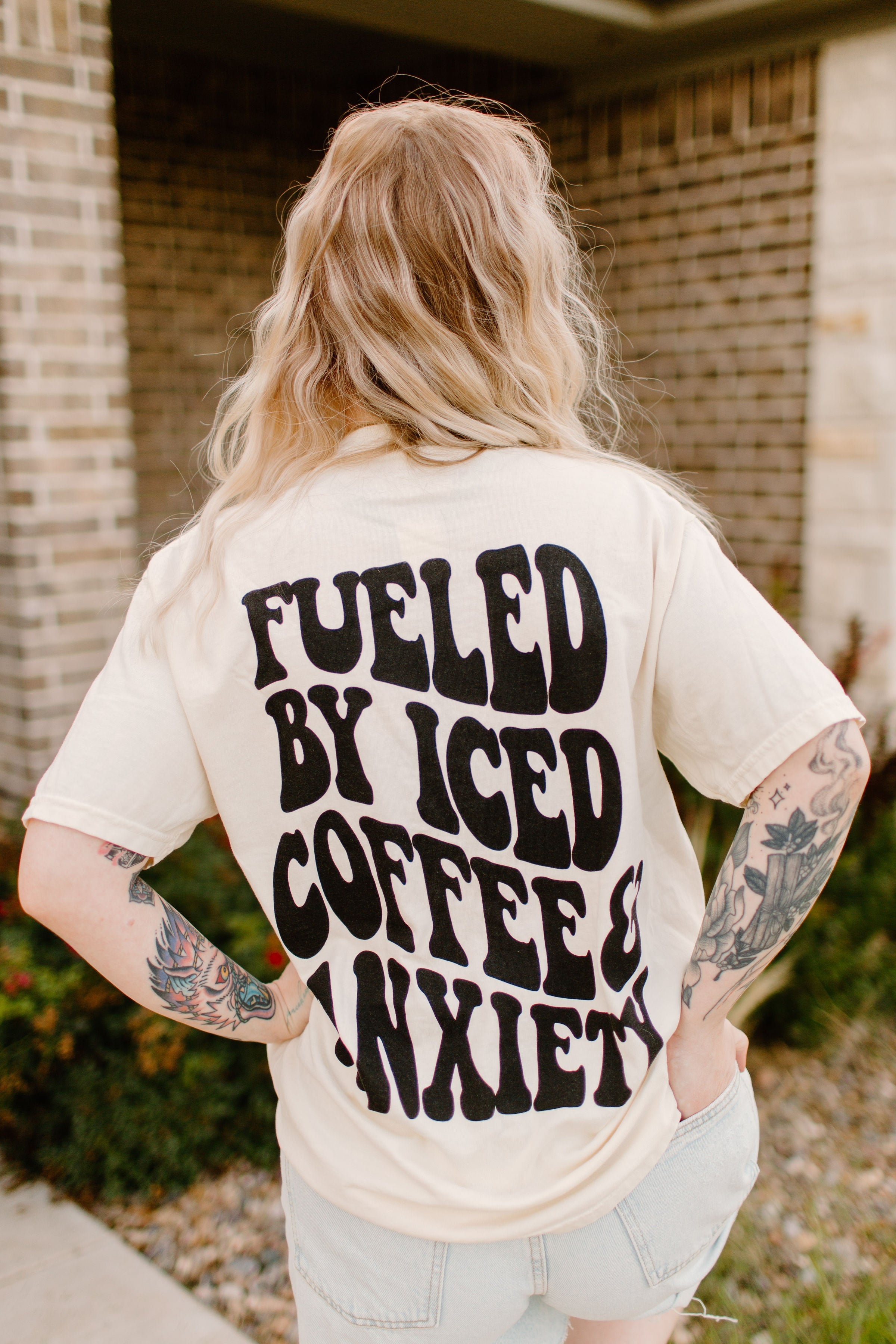 Graphic tee featuring "Fueled by iced coffee and anxiety" design on a casual unisex shirt from Shop Karma Tees.