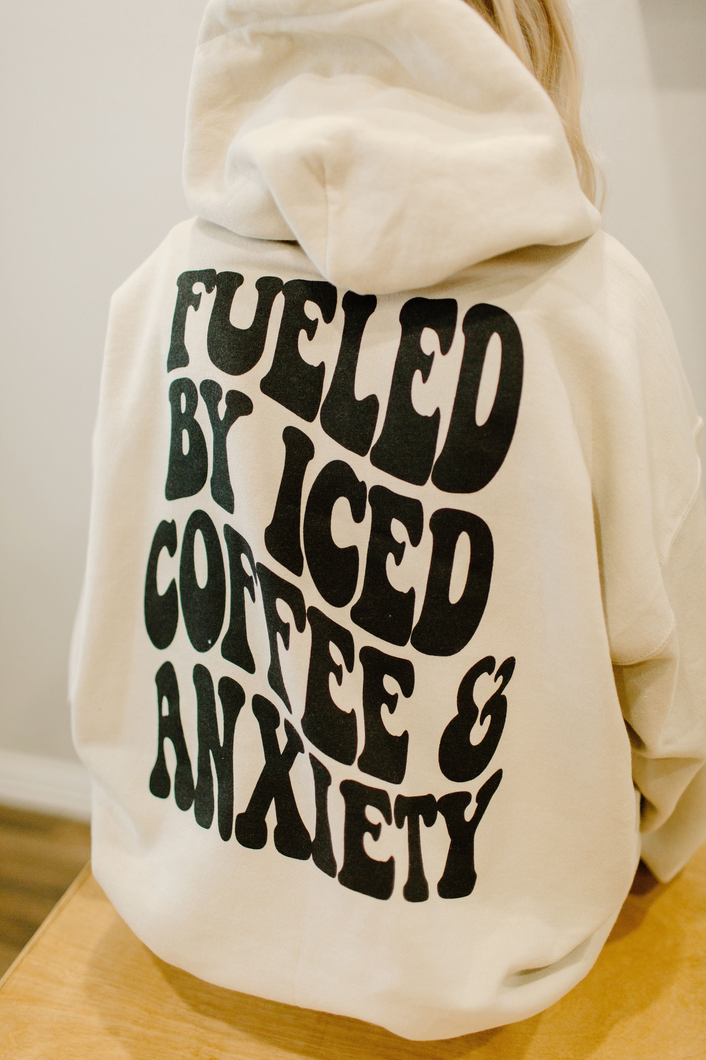 Graphical tee or sweatshirt featuring "Fueled by iced coffee and anxiety" slogan by Shop Karma Tees, with casual, comfortable design.