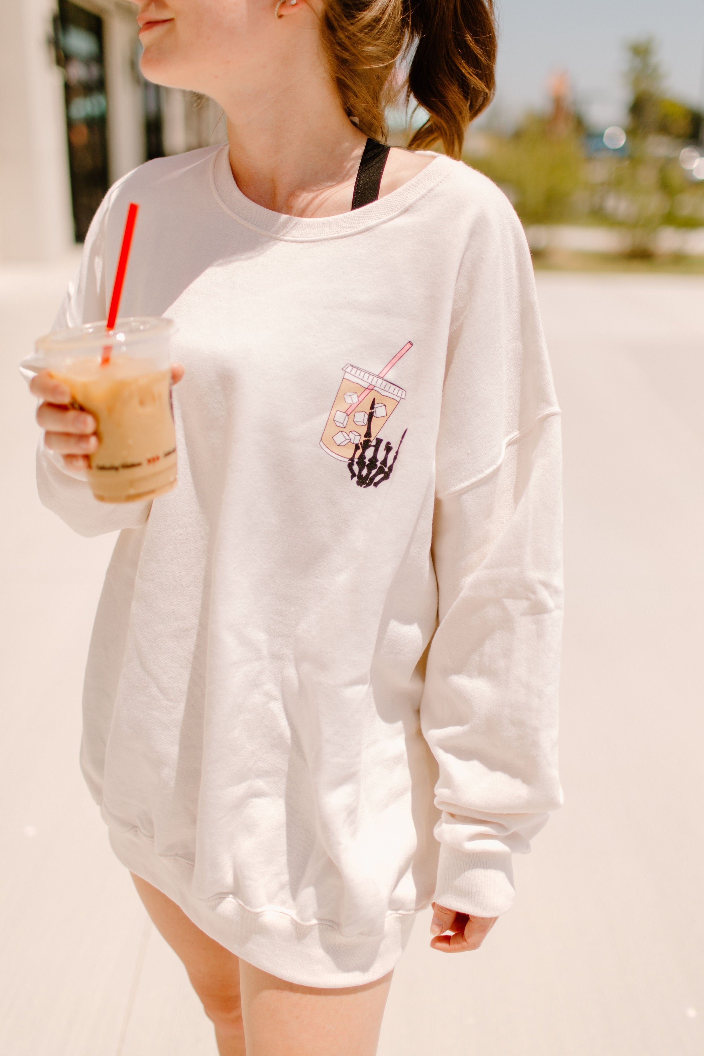 Gray graphic sweatshirt featuring "Fueled by iced coffee and anxiety" text, casual fit, soft fabric, and stylish design.