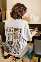 Gray graphic crewneck sweatshirt featuring the phrase "I Have More Tattoos Than I Do Friends" from Shop Karma Tees.