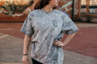 Overstimulated Moms Club graphic t-shirt from Shop Karma Tees, featuring bold text and casual fit, displayed on a hanger.