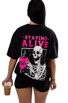 Small Shop Karma Tees Staying Alive short-sleeve graphic T-shirt displayed on a hanger.