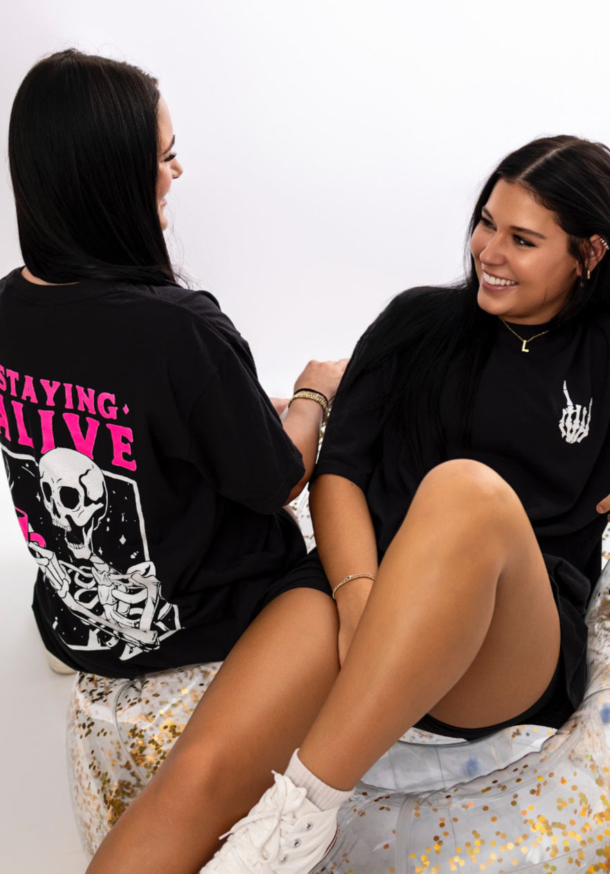 Graphic tee featuring Staying Alive design by Shop Karma Tees, with bold text and vibrant colors on a casual men's t-shirt.