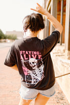 Black graphic tee featuring "Staying Alive" text and colorful design, from Shop Karma Tees.