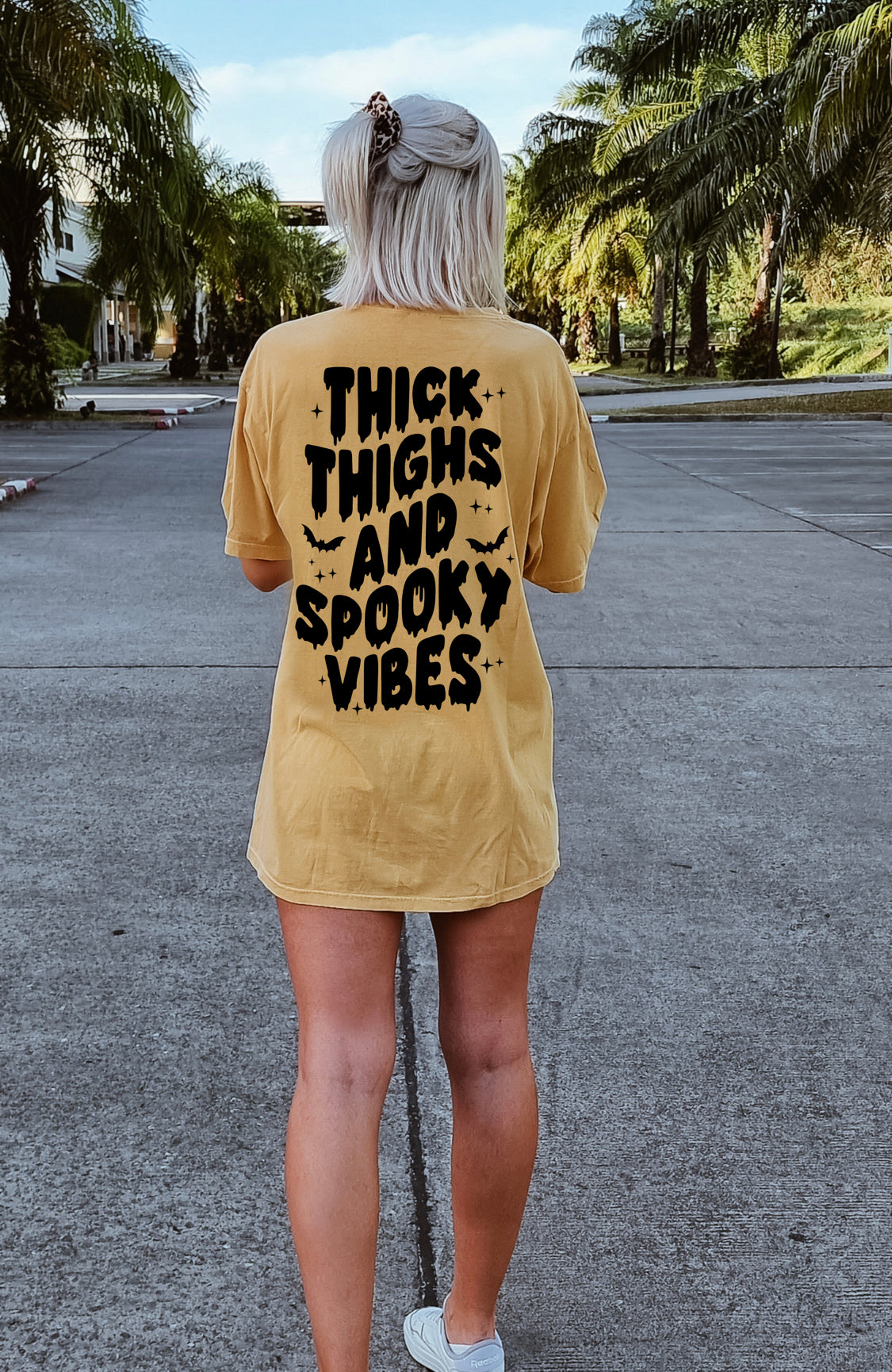 Black graphic tee from Shop Karma Tees featuring bold "Thick Thighs and Spooky Vibes" design on front.