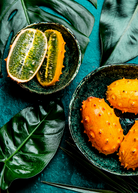 Orange Kiwano fruiting plant in coconut coir pot by Sow Exotic, showcasing the vibrant, spiky fruit and lush green foliage.
