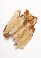 Astragalus herb in a coconut coir pot, shown with green, leafy stems of Astragalus membranaceus plant.