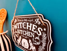 Wooden witchy décor sign with "Witches Kitchen" text, crafted by Spirit Nest, for home Halloween or witch-themed décor.