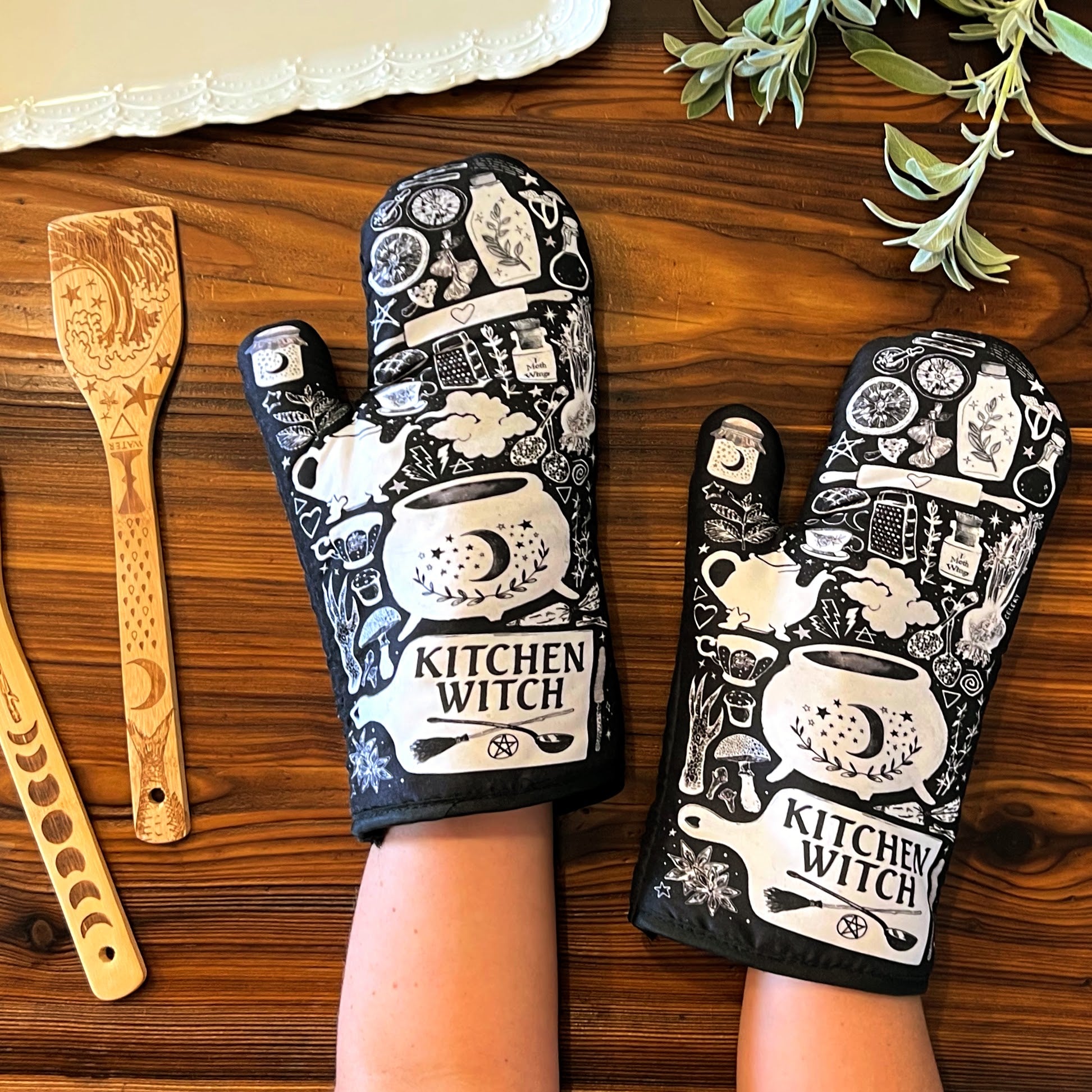 Purple and black kitchen oven mitts with witch and herb designs from Spirit Nest Kitchen Witch Oven Mitt Set, pair for cooking.
