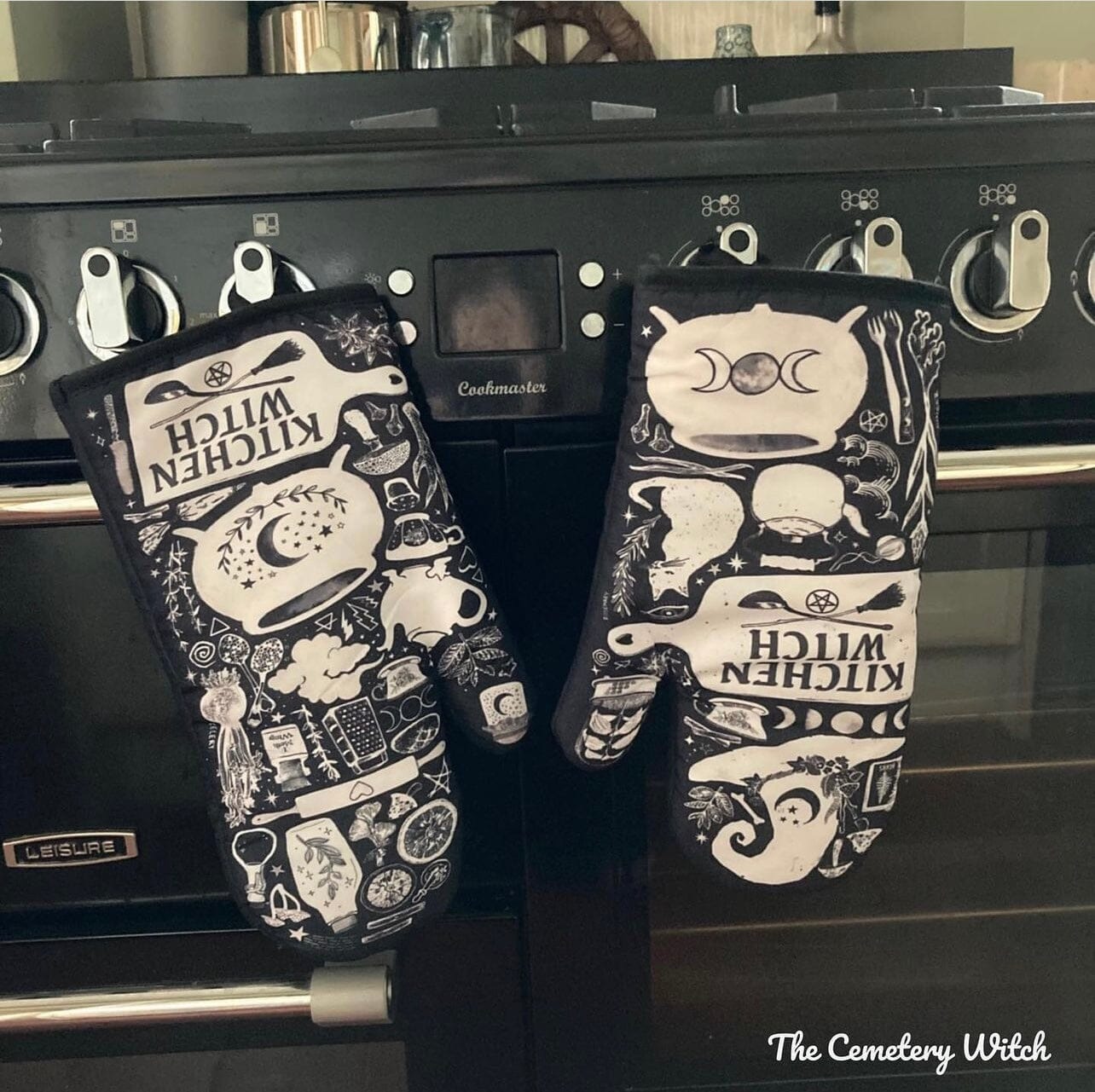 Purple and black Kitchen Witch oven mitt set with witch and herb design by Spirit Nest, perfect for kitchen safety and style.