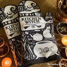 Purple and black witch-themed oven mitt set from Spirit Nest with herbs, featuring a kitchen witch design and comfortable fabric.