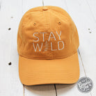 Relaxed mustard twill dad hat with "Stay Wild" embroidered in black, featuring a curved brim and adjustable strap.