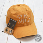 Relaxed fit mustard twill dad hat with "Stay Wild" embroidered text, casual cap style from The Graphic Tee brand