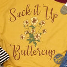 Unisex graphic t-shirt from The Graphic Tee featuring the "Suck It Up Buttercup" design on soft cotton fabric.
