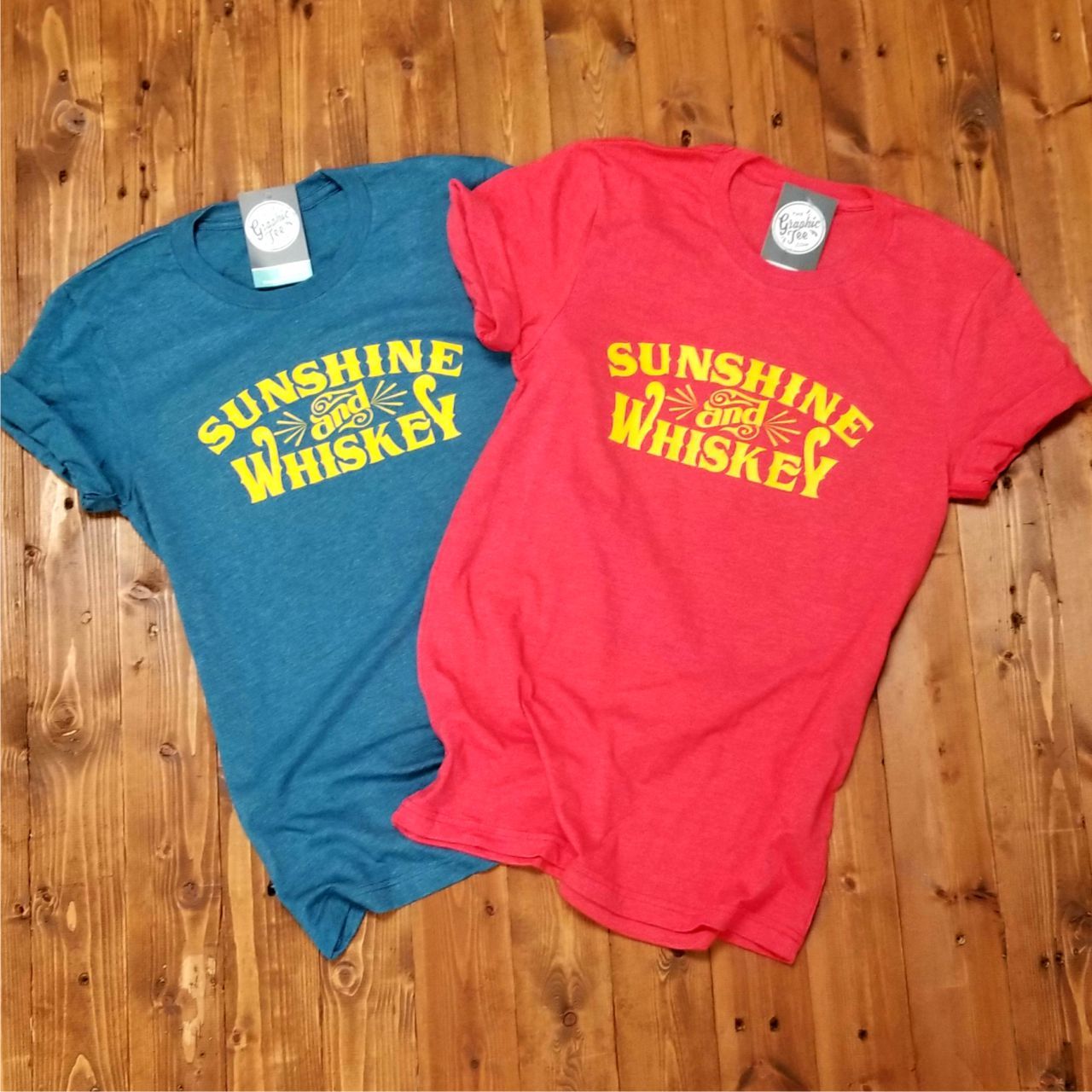 Sunshine and Whiskey unisex graphic T-shirt from The Graphic Tee featuring a vibrant sunset and whiskey bottle design.