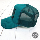 Jade foam trucker cap with "That Sounds Like My Husband's Problem" slogan by The Graphic Tee, adjustable mesh back, casual style.