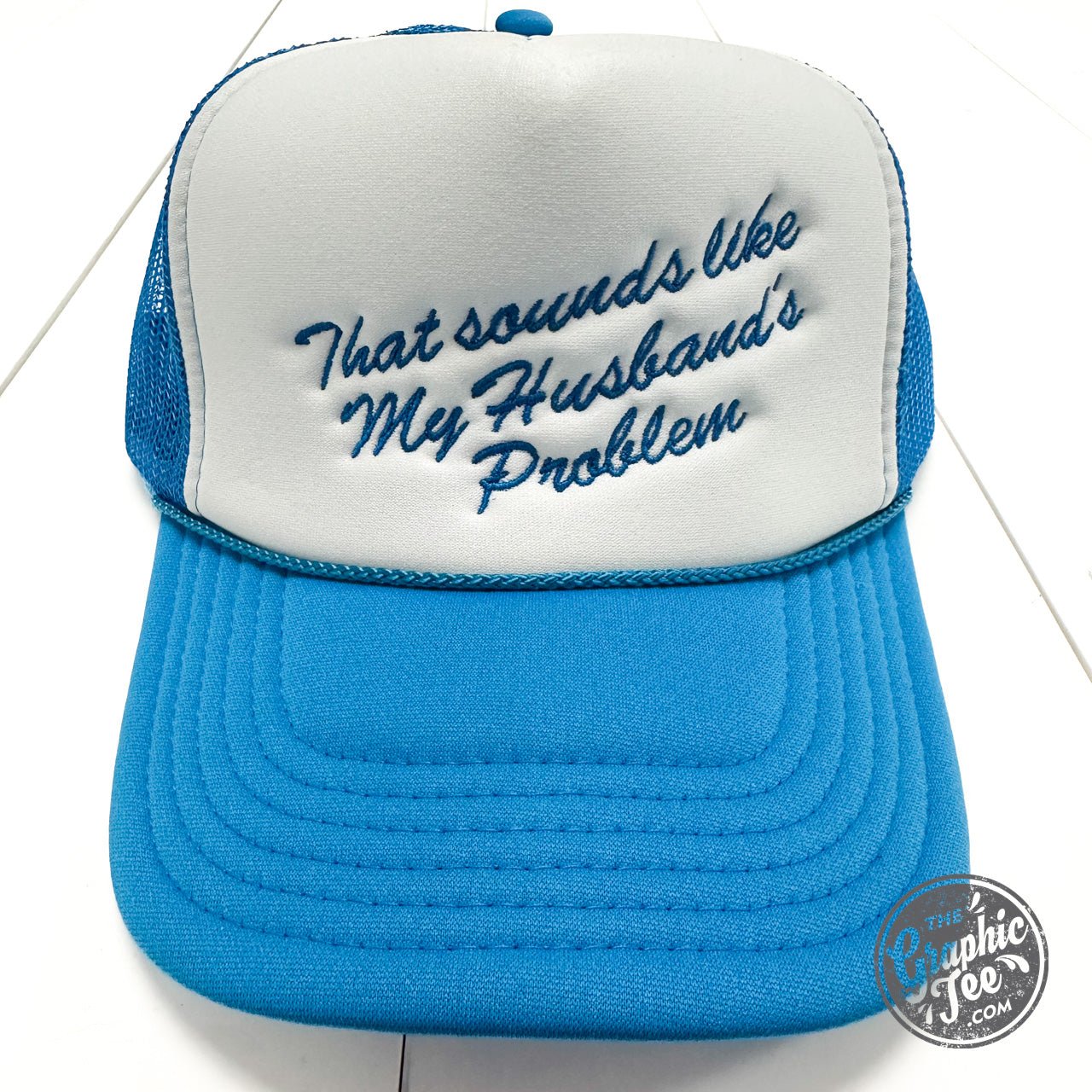 That Sounds Like My Husband's Problem trucker cap by The Graphic Tee, featuring a casual mesh back and humorous printed front design.