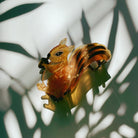 Velvet claw hair clip featuring a squirrel holding an acorn design, from The Bullish Store, shown with a travel bag.