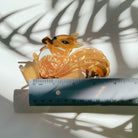 Velvet squirrel-shaped hair claw clip holding an acorn, from The Bullish Store, with a velvet travel bag in the background.