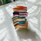 Velvet Claws stack of books hair clip by The Bullish Store, featuring a velvet claw design, shown with a travel bag for accessories.