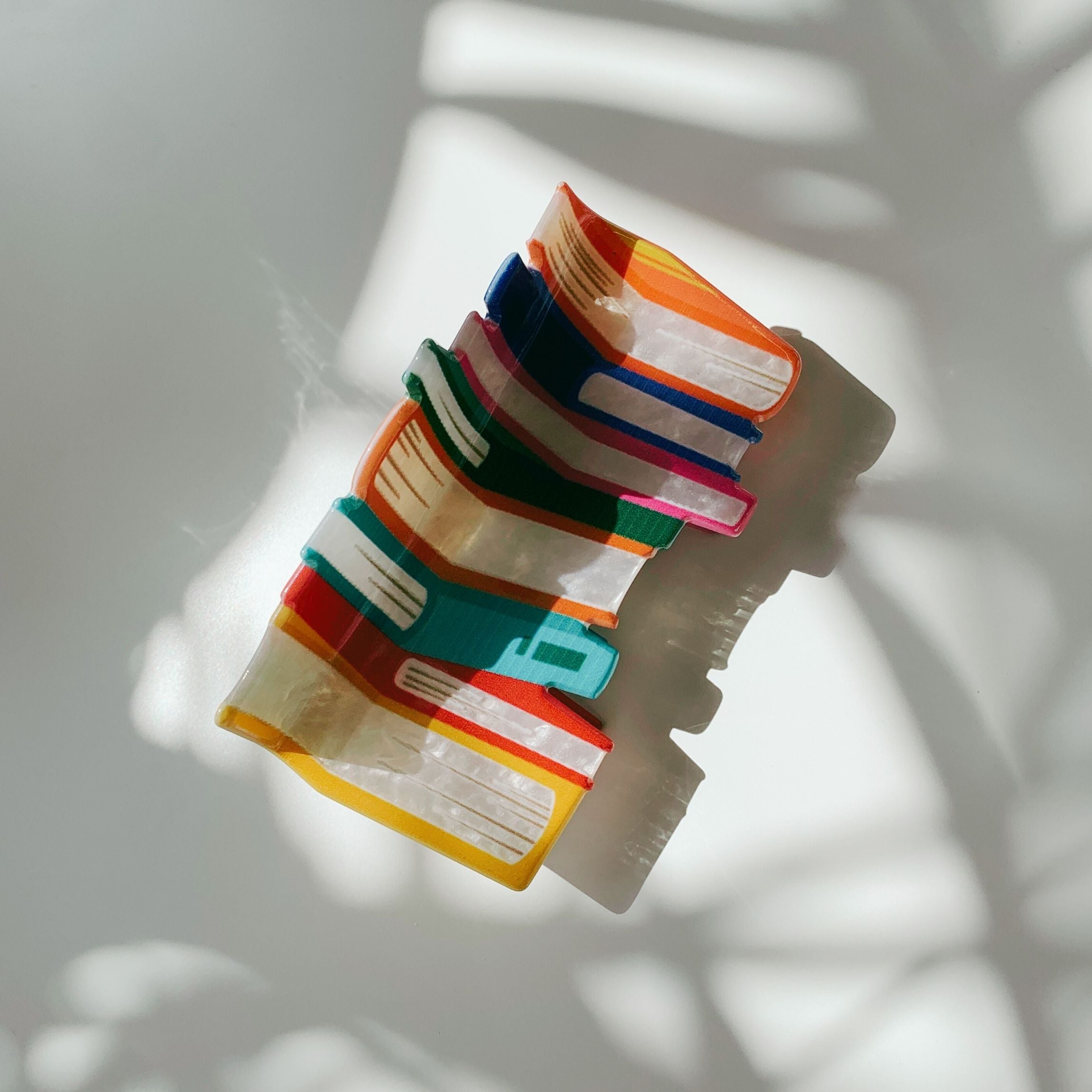 Velvet Claws stack of books hair clip in a velvet travel bag, stylish accessory from The Bullish Store with claw design.