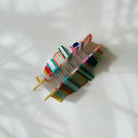 Velvet Claws stack of books hair clip by The Bullish Store featuring a plush velvet claw design in a travel bag.