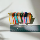 Velvet Claws Stack of Books hair clip from The Bullish Store featuring a velvet claw design, shown with a travel bag in the image.