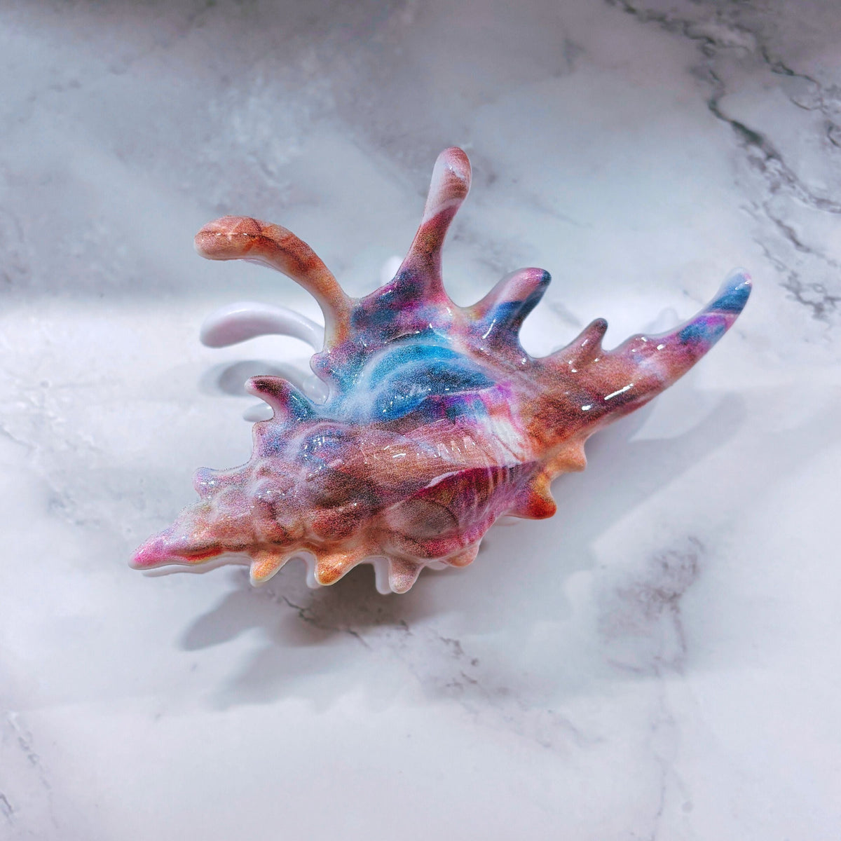Velvet Claws conch shell hair clip in mermaid colors, realistic design, perfect for securing hair with a stylish tropical look.