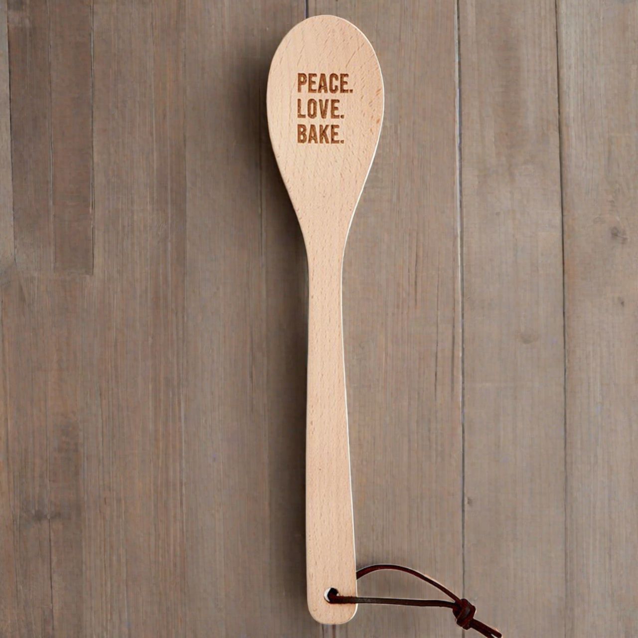 Wooden cooking spoon with "Peace Love Bake" engraving in muslin gift bag, perfect for kitchen utensils and baking enthusiasts.