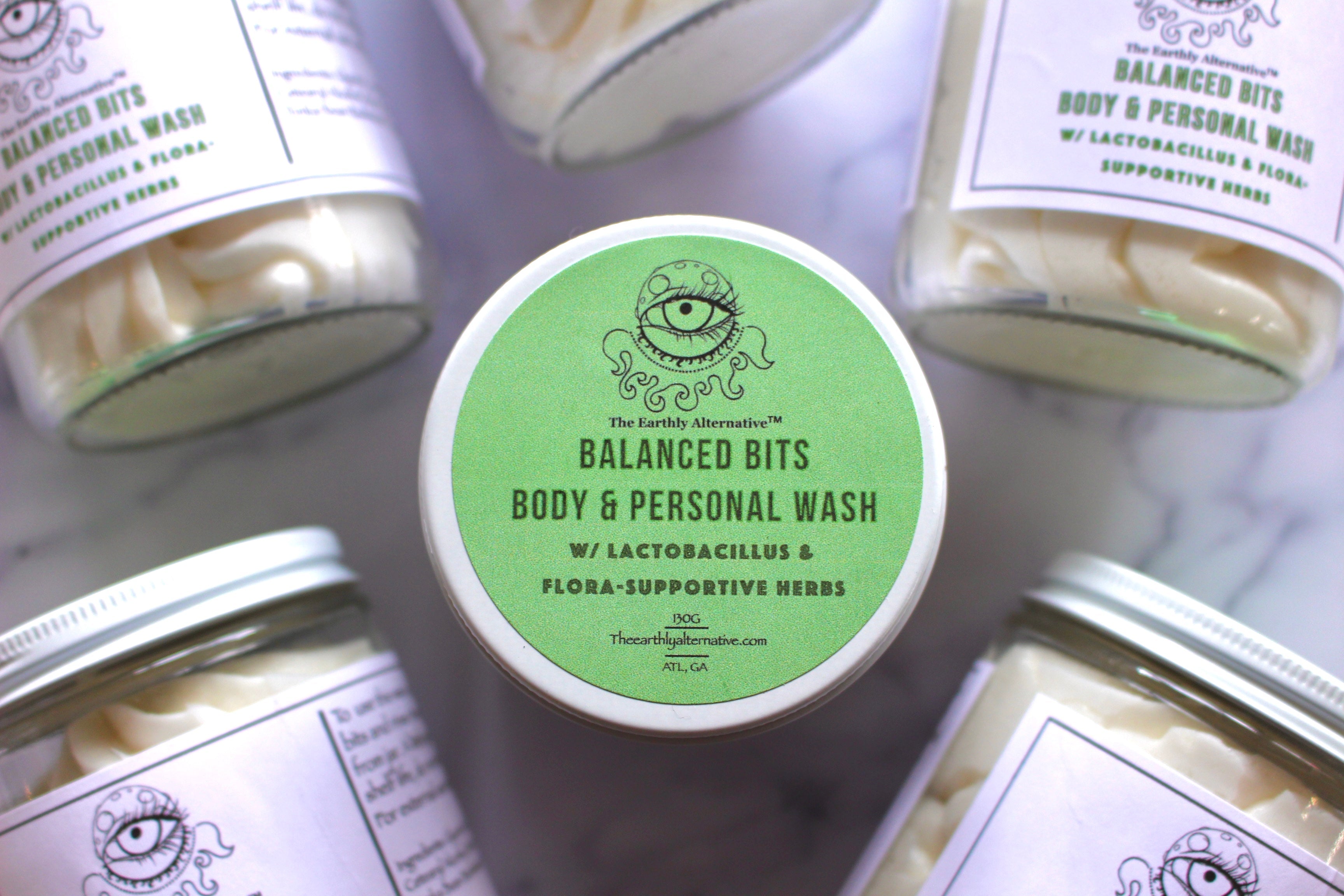 The Earthly Alternative Balanced Bits Body & Personal Wash in a clear 8 oz glass jar with natural ingredients visible.
