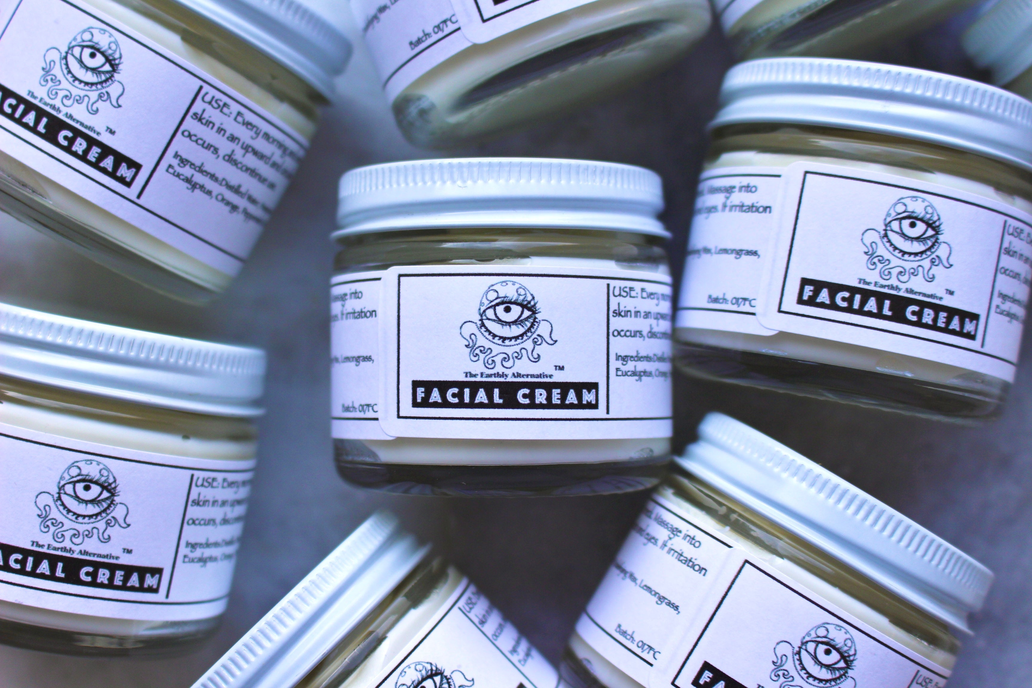 Cream jar labeled "Facial Cream" from The Earthly Alternative with a sleek, minimalist design on a neutral background.