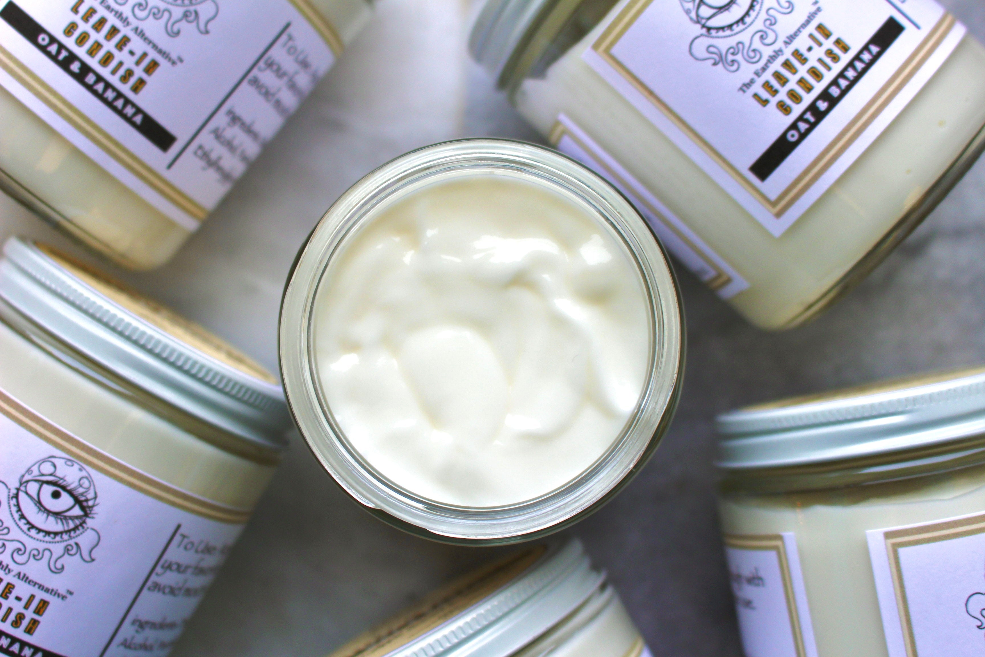 Creamy oat and banana leave-in conditioner by The Earthly Alternative, shown in a clear container with the product label.