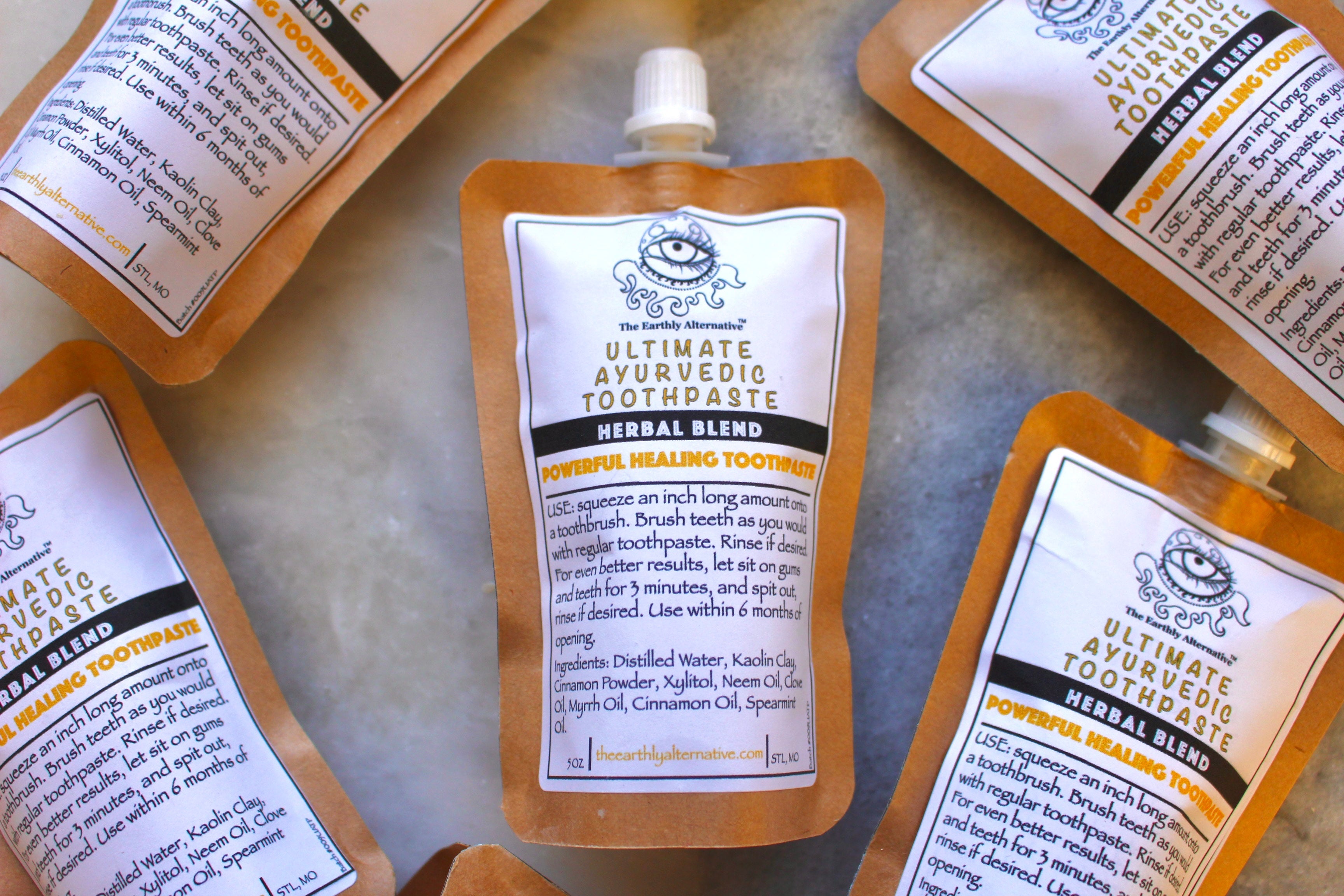 Tube of The Earthly Alternative Ultimate Ayurvedic Toothpaste with natural herbal ingredients and a white and green packaging design.