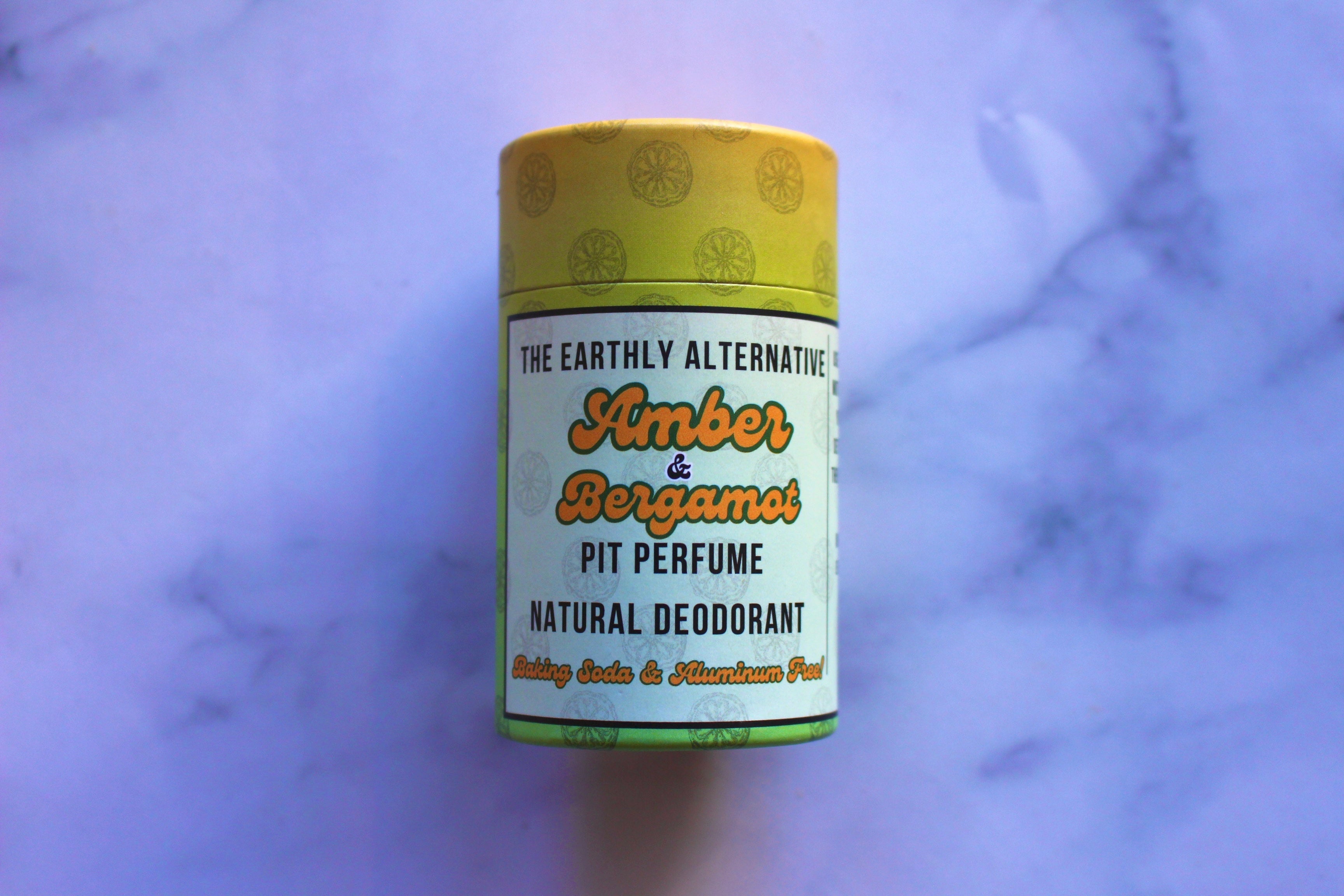 The Earthly Alternative Pit Perfume Deodorant in amber bergamot scent, natural deodorant stick with floral and citrus aroma.