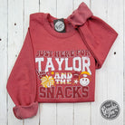 Heather sport scarlet crewneck sweatshirt from The Graphic Tee featuring "Just Here For Taylor And The Snacks" graphic design.