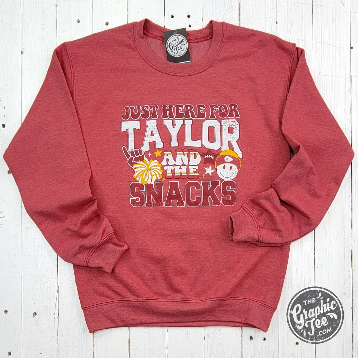 Heather Sport Scarlet crewneck sweatshirt featuring "Just Here For Taylor And The Snacks" graphic logo, by The Graphic Tee.
