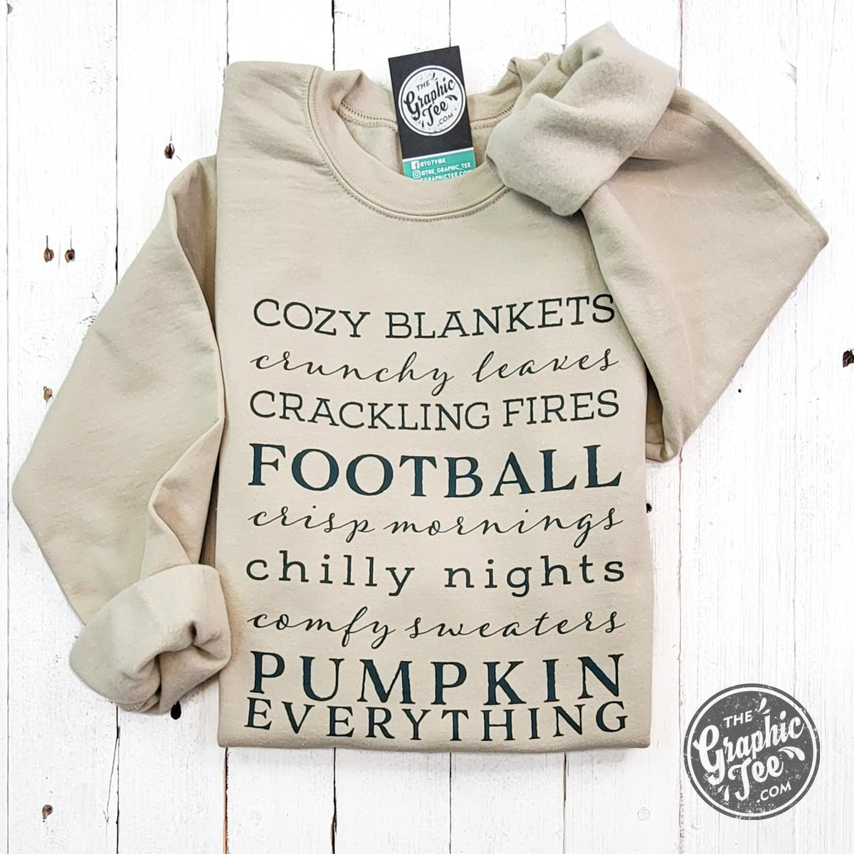 The Graphic Tee Autumn Words Cozy Sand Crewneck Sweatshirt with autumn-themed text and a soft, comfortable fabric.