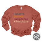 Long sleeve graphic tee from The Graphic Tee featuring sunset, s'mores, campfire, and pumpkin illustrations.