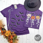 Purple Halloween short sleeve graphic tee by The Graphic Tee featuring bats and dancing skeletons on front and back.