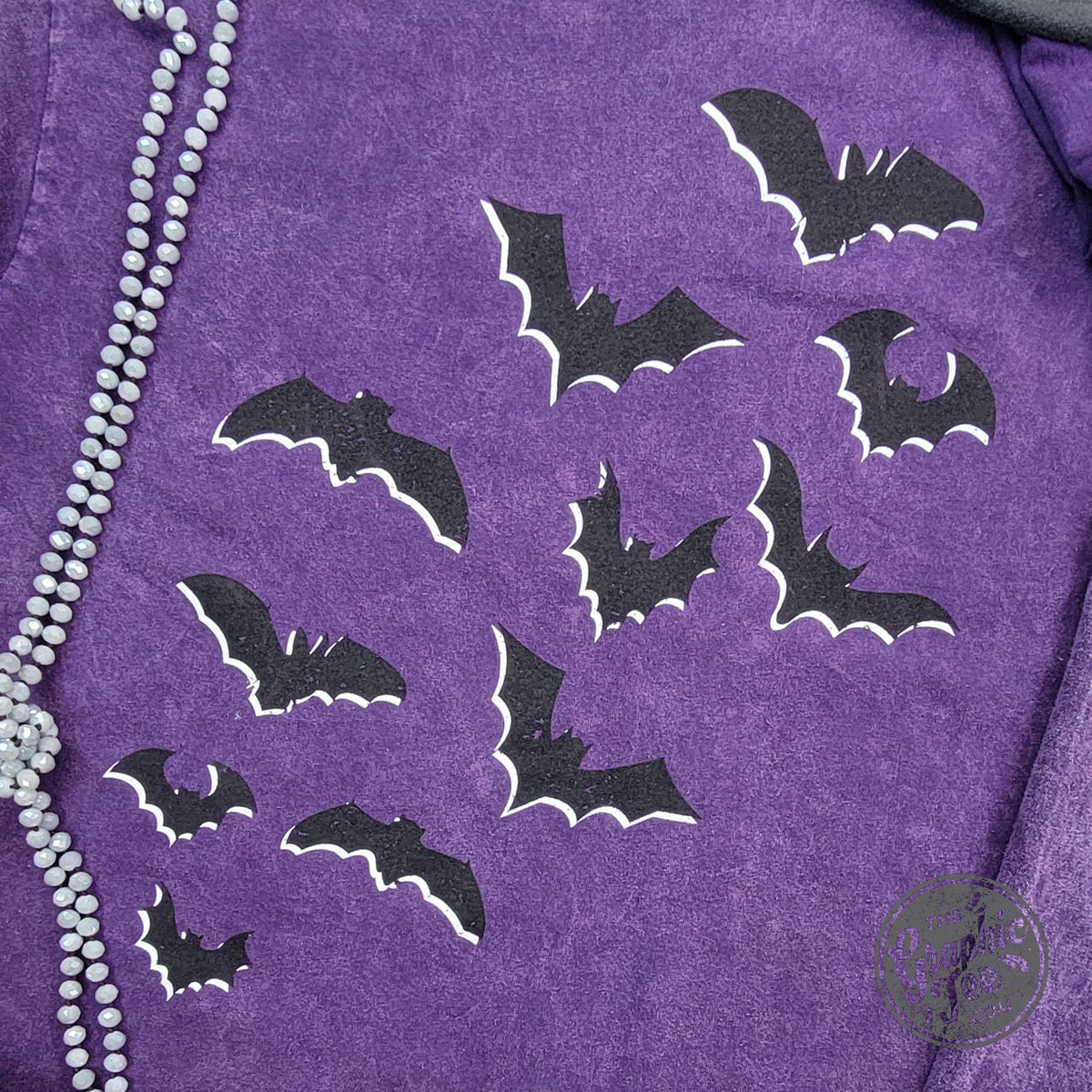 Purple Halloween graphic tee by The Graphic Tee featuring front and back bats and dancing skeletons on a mineral wash short sleeve shirt.