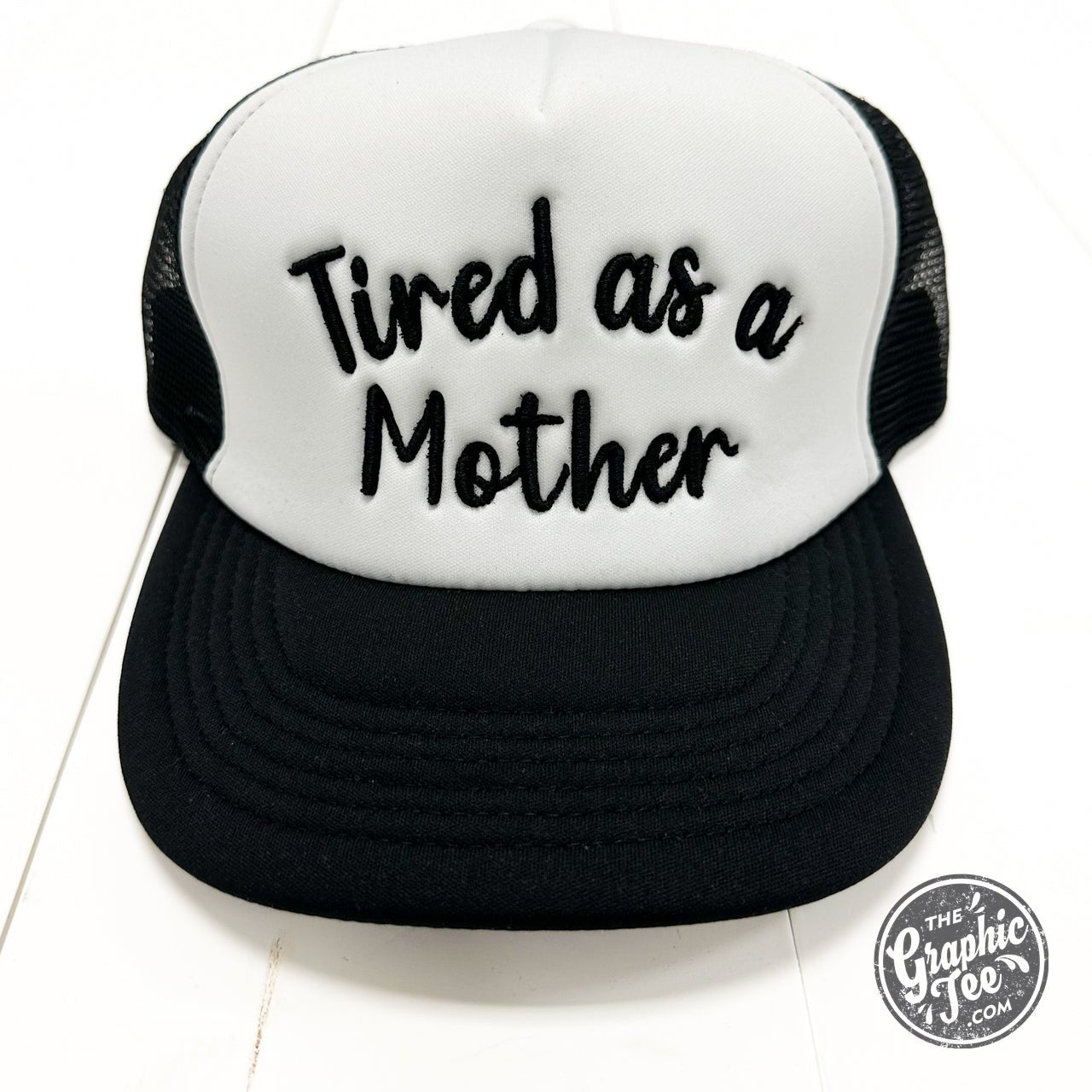 Tired As A Mother foam trucker cap by The Graphic Tee, featuring a casual mesh design and bold printed slogan on the front.