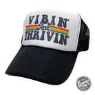 Foam trucker cap with "Vibin' and Thrivin'" slogan, featuring adjustable snapback closure and breathable mesh back.