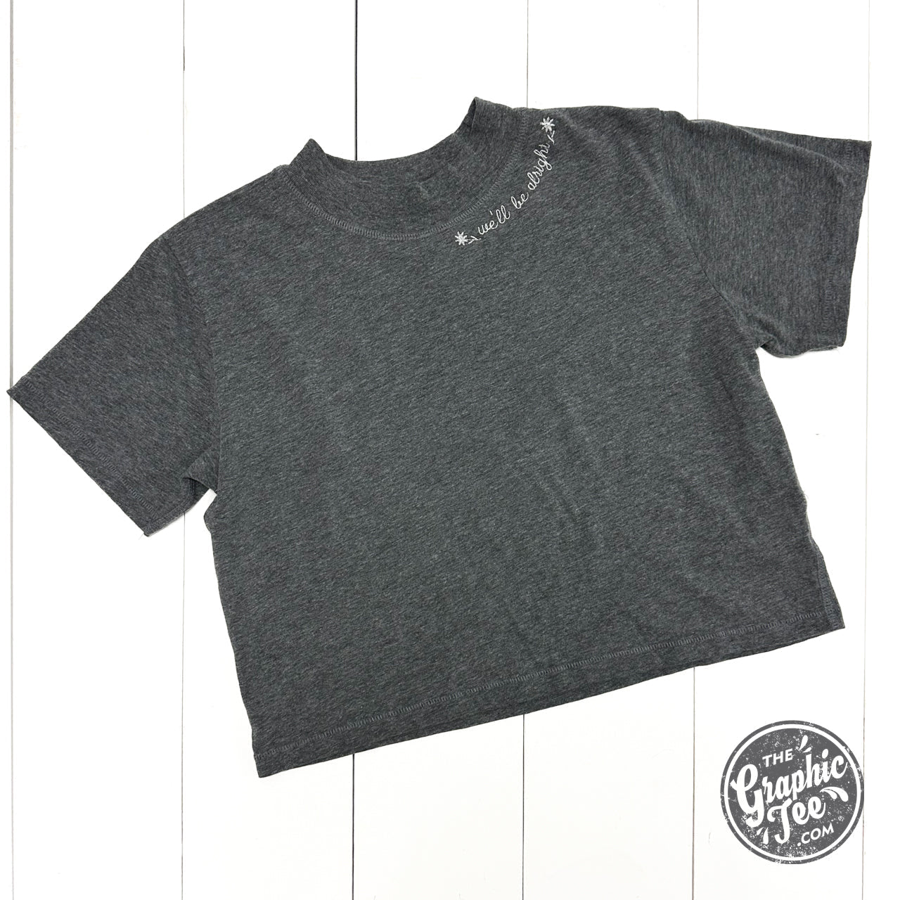Embroidered waist-length crop tee from The Graphic Tee with "We'll Be Alright" design, casual SS graphic tee for women.
