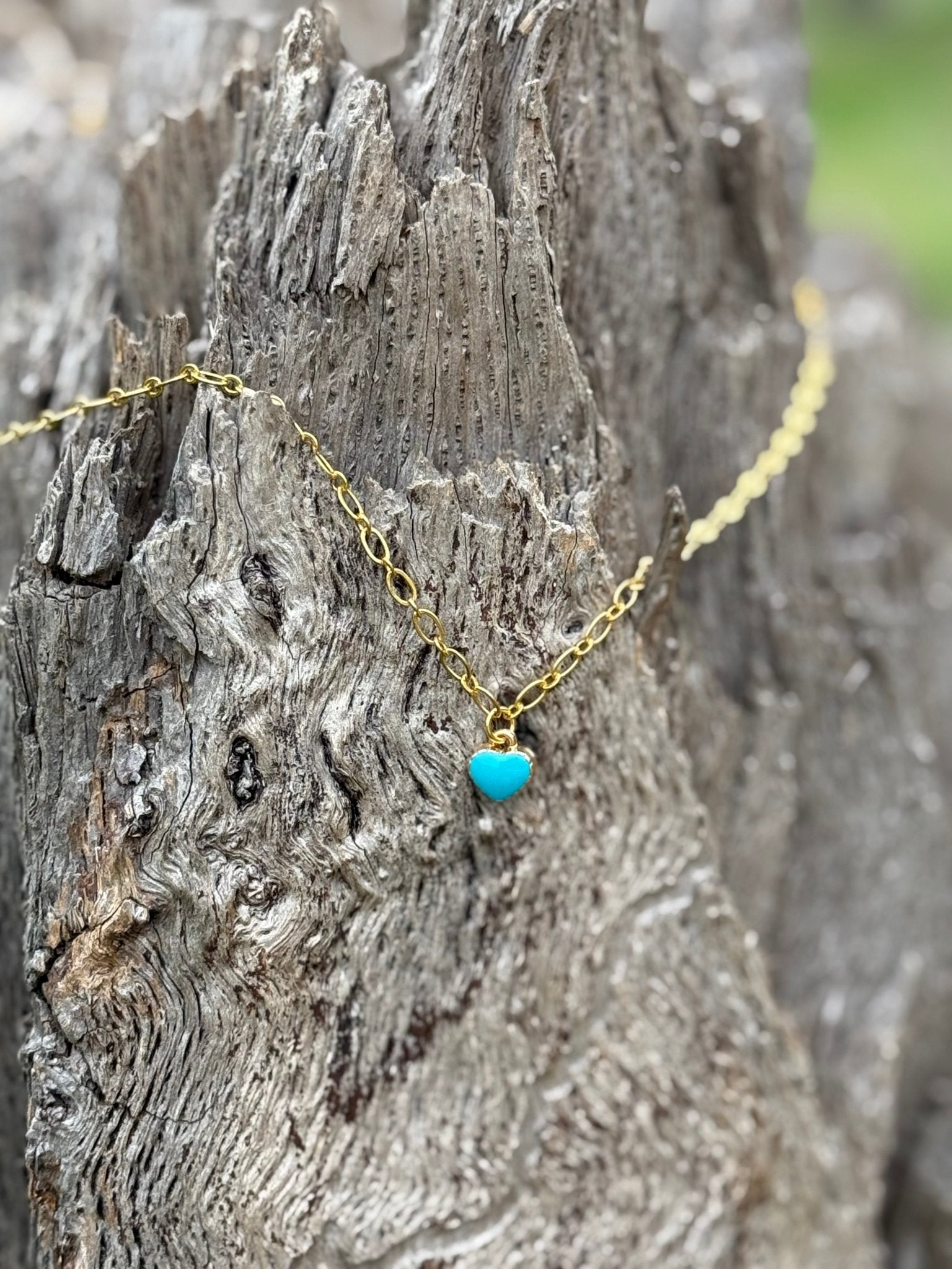 Turquoise heart pendant on a gold chain necklace by Wild Junkie, close-up of the jewelry showcasing vibrant turquoise and gold details.